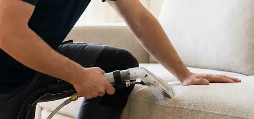 Professional upholstery cleaner deep-cleaning a fabric sofa with a handheld extraction tool, Ogden, UT.